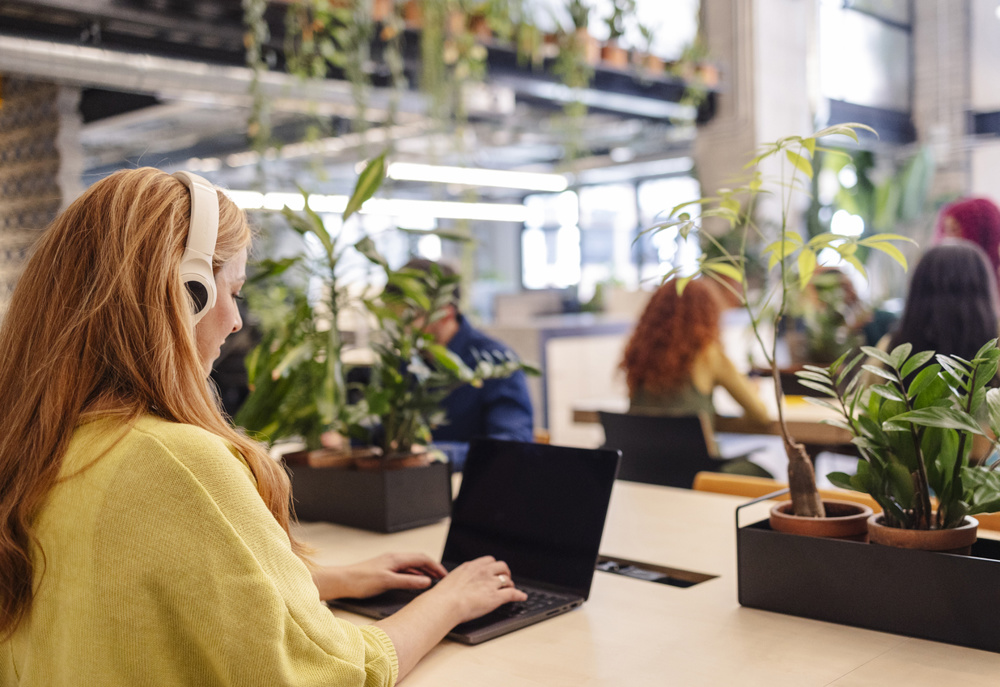 A woman working on a laptop in a green coworking space