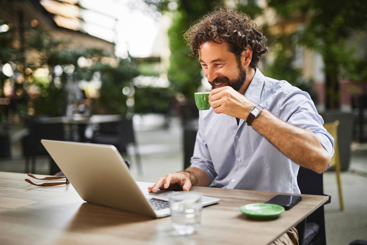 a man enjoying a coffee while working on a laptop in an outdoor cafe