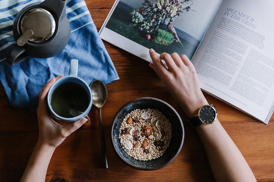 a table with a book, tea cup, plate of grains