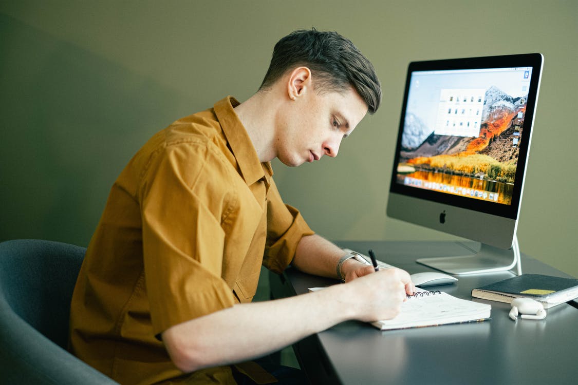man taking notes in front of computer