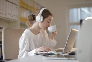 woman wearing headphones using white laptop