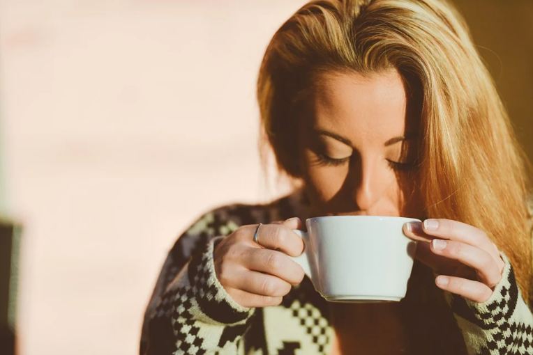 a woman drinking from a coffee cup