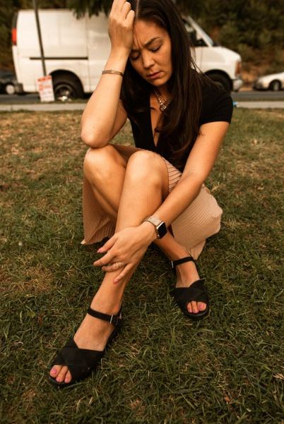 A Picture of a Stressed Women Sitting on the Grass.