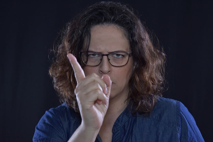 A woman with an angry face, pointing her index finger