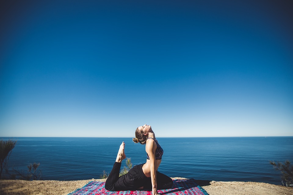 a woman doing a yoga pose near the ocean