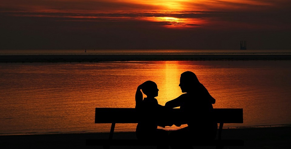 warm sunset, clear and calm sea, silhouette of a mother and daughter talking
