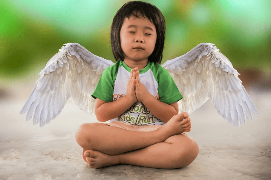 a young girl in cross-sitting position, hands clasped together as if praying