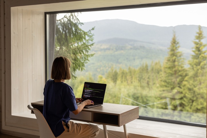woman-works-on-laptop-remotely-in-house-on-nature